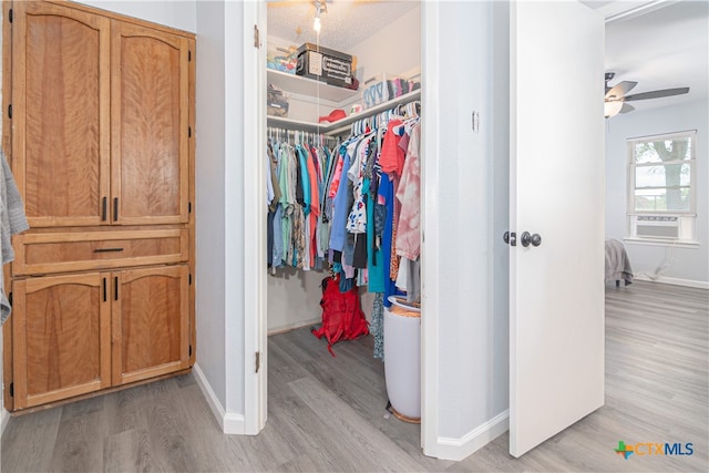 walk in closet featuring light hardwood / wood-style floors, cooling unit, and ceiling fan