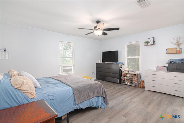 bedroom with light hardwood / wood-style floors, ceiling fan, and cooling unit