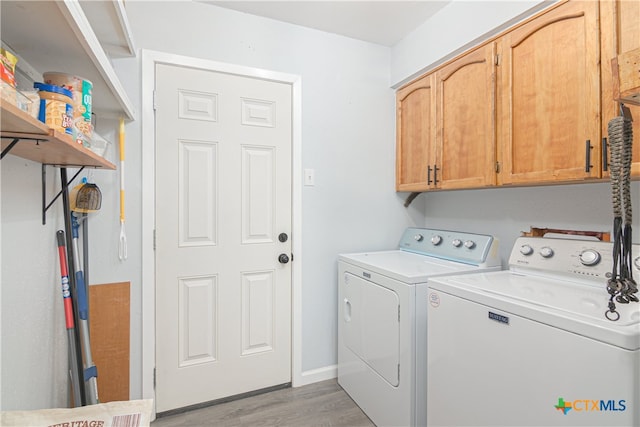 clothes washing area featuring washing machine and dryer, cabinets, and light hardwood / wood-style flooring