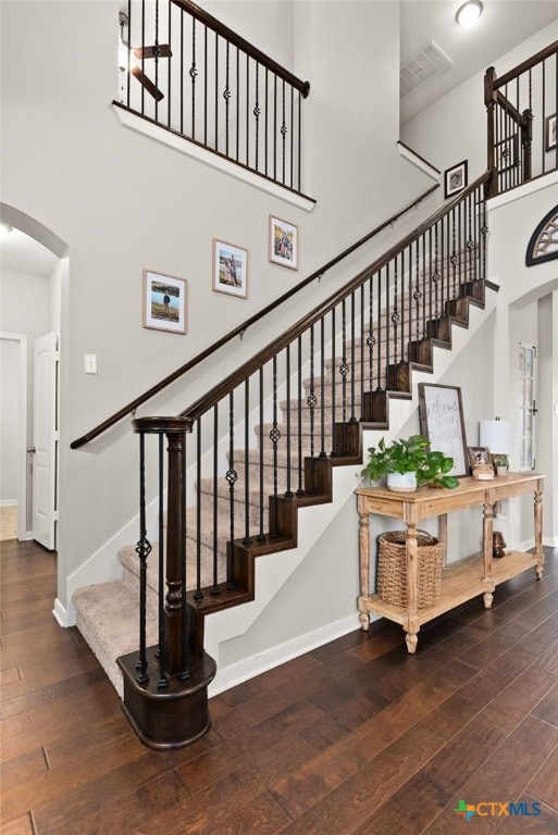 stairs with a high ceiling and wood-type flooring