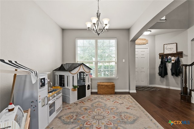 game room with dark hardwood / wood-style flooring and an inviting chandelier