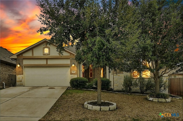 view of front facade featuring stone siding, fence, an attached garage, and concrete driveway