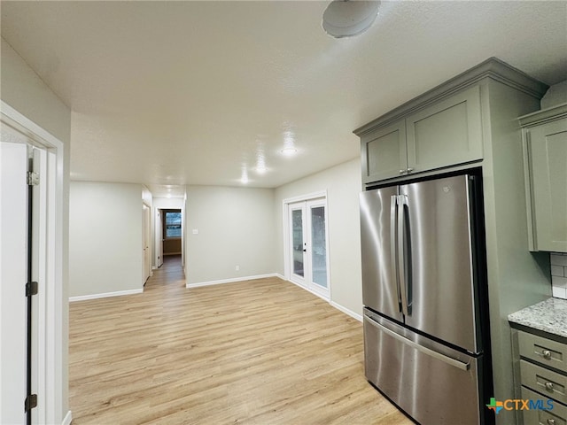 kitchen featuring french doors, light wood-style flooring, freestanding refrigerator, and baseboards