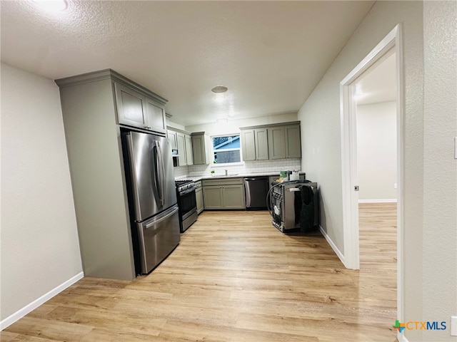 kitchen featuring stainless steel appliances, baseboards, decorative backsplash, and light wood finished floors