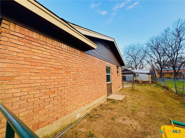 view of home's exterior featuring brick siding, fence, and a lawn