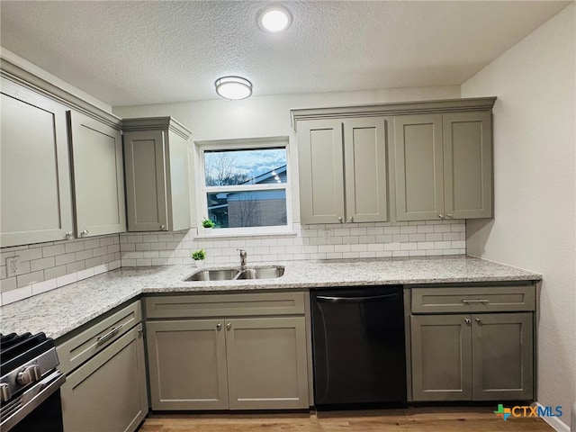 kitchen featuring dishwashing machine, gray cabinetry, a sink, backsplash, and stainless steel gas stove