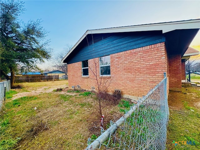 view of home's exterior featuring crawl space, brick siding, and fence