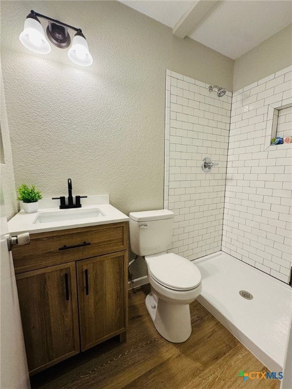 bathroom with a stall shower, a textured wall, toilet, wood finished floors, and vanity