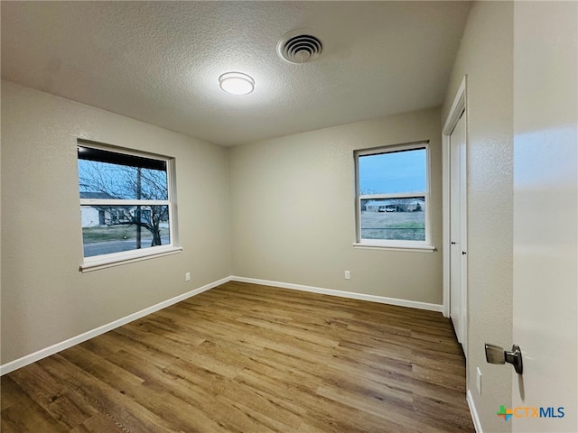 unfurnished bedroom with wood finished floors, visible vents, and baseboards