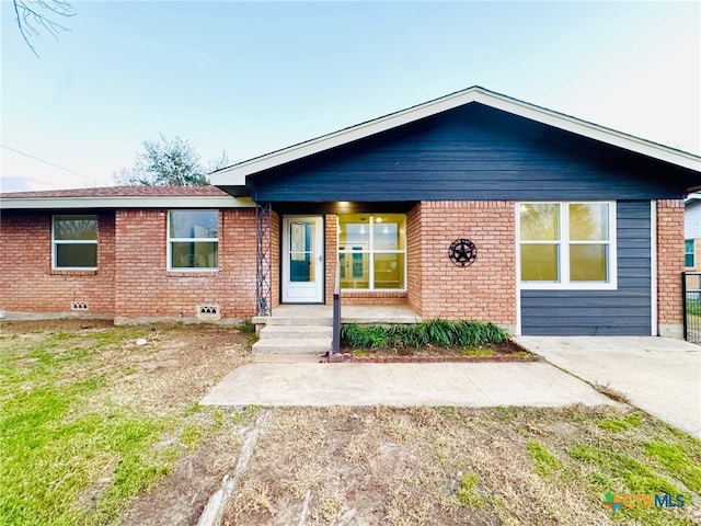 single story home with covered porch and brick siding