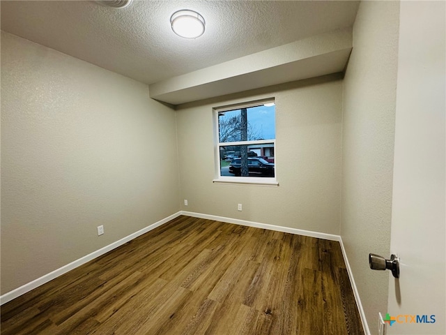 spare room featuring a textured ceiling, baseboards, and wood finished floors