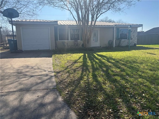 single story home with a front yard, concrete driveway, metal roof, and an attached garage