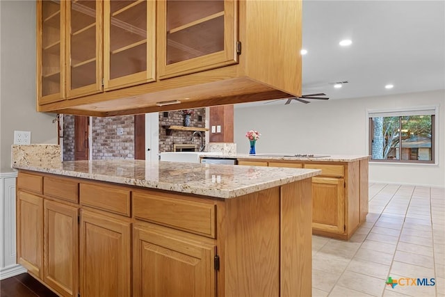 221 W Tanglewood Dr, New Braunfels, TX 78130 - kitchen with a peninsula, black electric stovetop, light stone countertops, glass insert cabinets, and decorative backsplash
