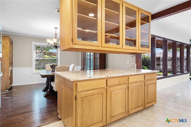 221 W Tanglewood Dr, New Braunfels, TX 78130 - kitchen featuring a chandelier, glass insert cabinets, light stone countertops, wainscoting, and ornamental molding