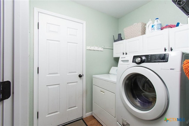 washroom with cabinets, washing machine and dryer, and hardwood / wood-style flooring