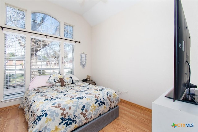 bedroom with light wood-type flooring, multiple windows, and lofted ceiling