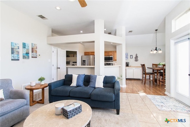 living room with light tile patterned floors and ceiling fan with notable chandelier