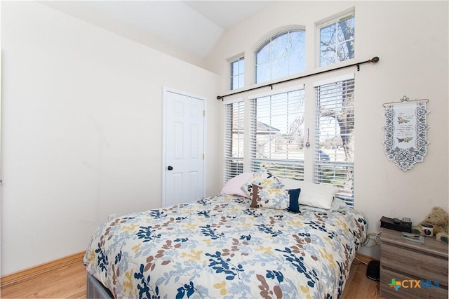 bedroom featuring light hardwood / wood-style flooring and lofted ceiling