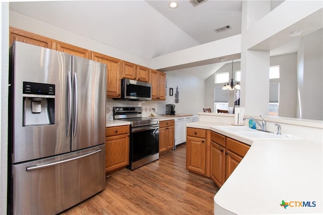 kitchen featuring stainless steel appliances, sink, decorative light fixtures, a chandelier, and lofted ceiling