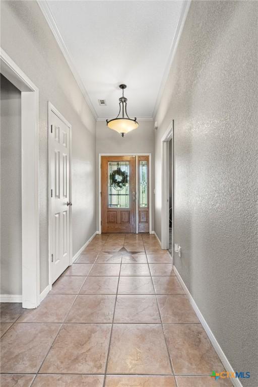 3197 Robin Ln, Kempner, TX 76539 - doorway to outside with ornamental molding, light tile patterned floors, a textured wall, and baseboards