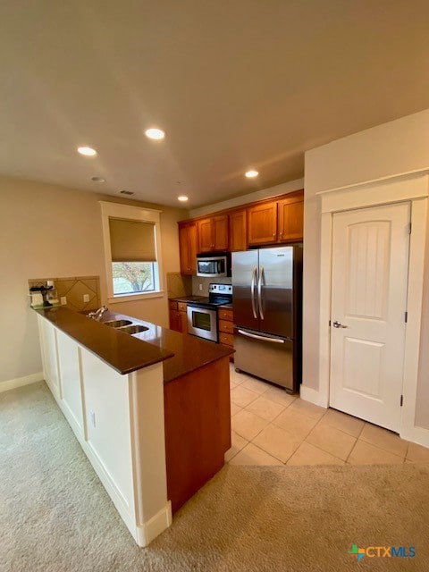 kitchen with sink, kitchen peninsula, light colored carpet, and stainless steel appliances