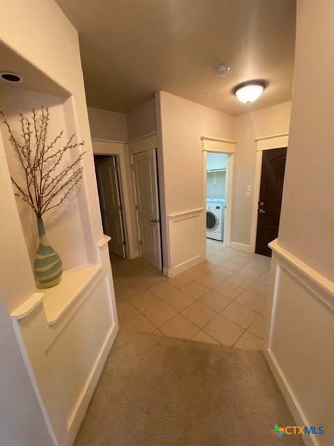 hallway featuring washer / dryer and light tile patterned floors