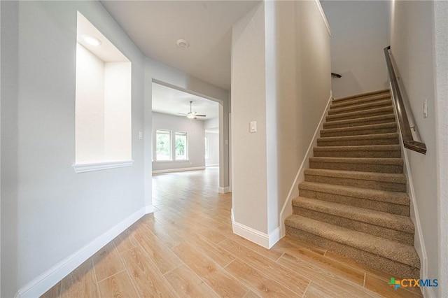 staircase featuring ceiling fan and wood-type flooring