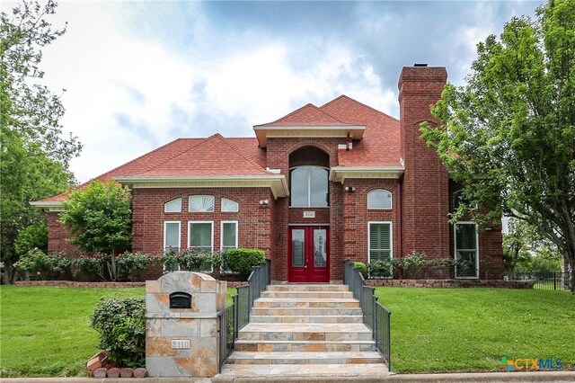 2110 Lakeview Loop, Killeen, TX 76543 - view of front facade with a chimney, fence, brick siding, french doors, and a front lawn