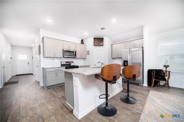 kitchen with a kitchen island with sink, appliances with stainless steel finishes, a healthy amount of sunlight, and gray cabinetry