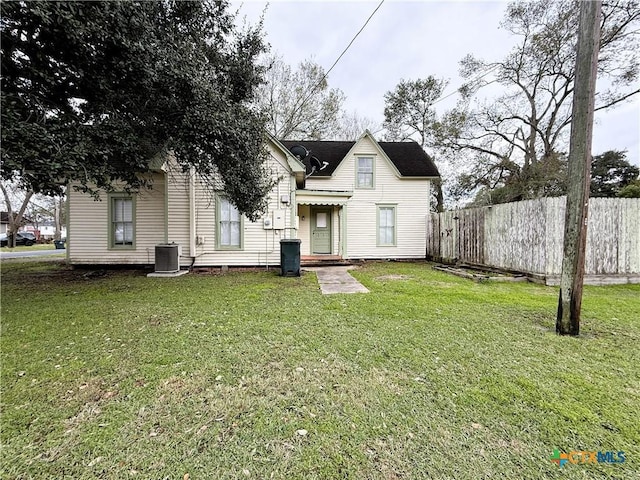 rear view of property featuring central AC unit and a lawn