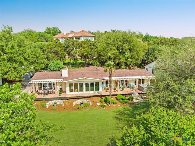 back of house featuring a lawn and a patio
