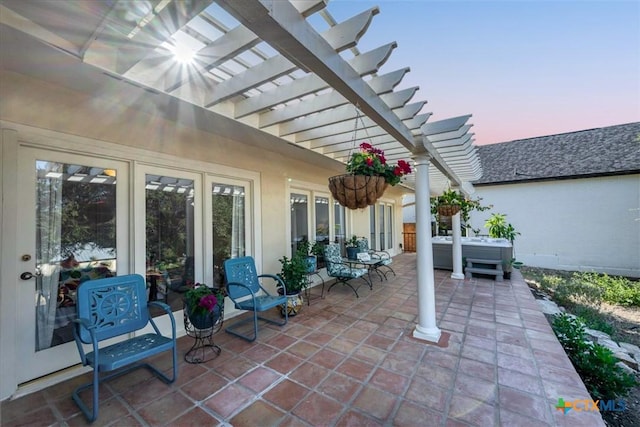 patio terrace at dusk with a hot tub and a pergola