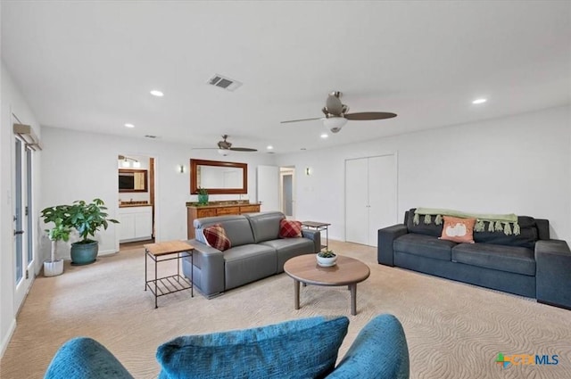 living room with light carpet, a ceiling fan, visible vents, and recessed lighting