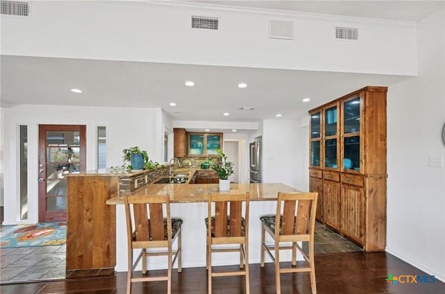 kitchen featuring sink, a breakfast bar area, dark hardwood / wood-style flooring, high end refrigerator, and kitchen peninsula