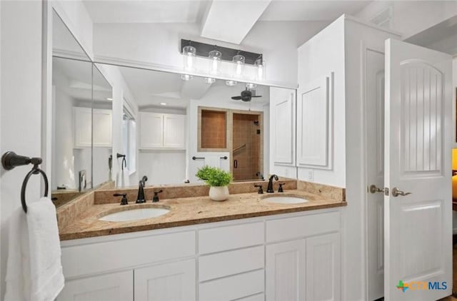 full bathroom featuring double vanity, tiled shower, and a sink