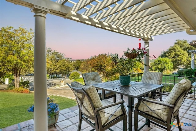 patio terrace at dusk featuring a pergola and a lawn