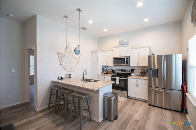 kitchen with appliances with stainless steel finishes, a sink, visible vents, and light wood-style floors
