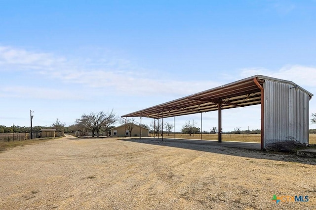 exterior space featuring dirt driveway and a carport