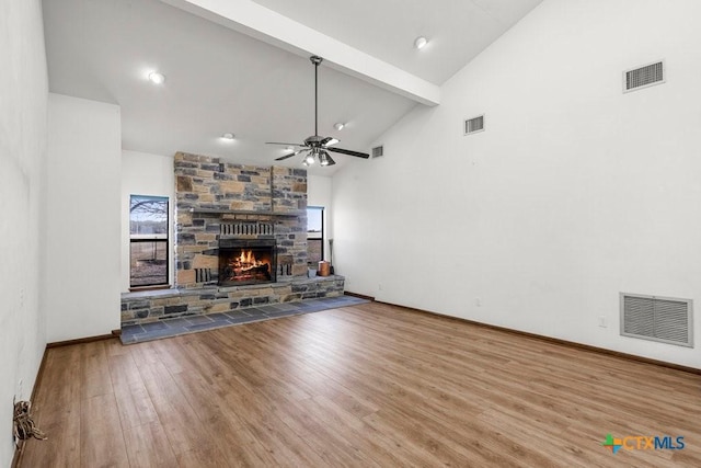 unfurnished living room featuring beam ceiling, a fireplace, visible vents, wood finished floors, and high vaulted ceiling