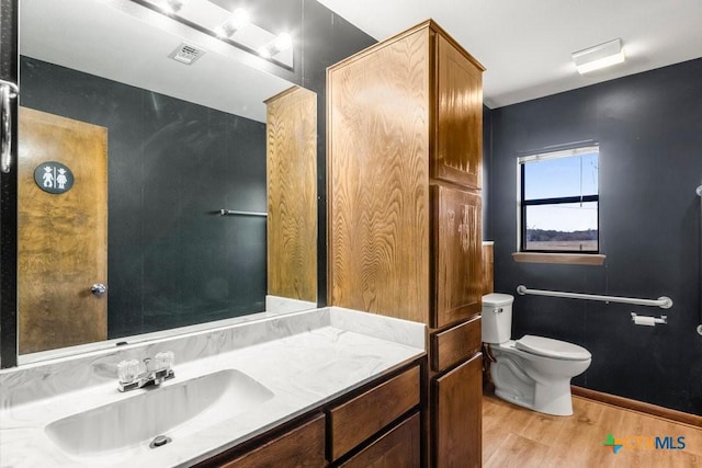 bathroom featuring toilet, wood finished floors, visible vents, vanity, and baseboards