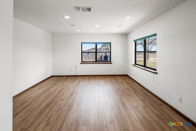 unfurnished room featuring baseboards, visible vents, wood finished floors, and recessed lighting