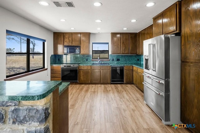 kitchen with dark countertops, visible vents, light wood finished floors, and black appliances