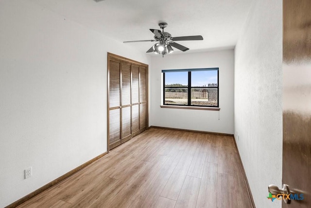 empty room featuring wood finished floors, a ceiling fan, and baseboards