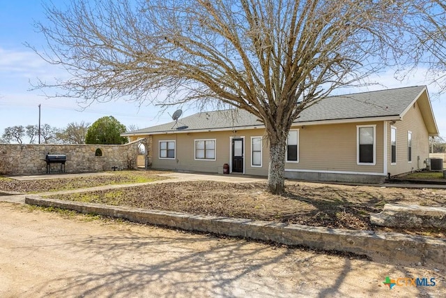 single story home featuring a shingled roof, fence, and cooling unit