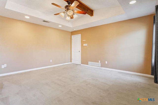 carpeted spare room featuring a raised ceiling, ceiling fan, and lofted ceiling with beams