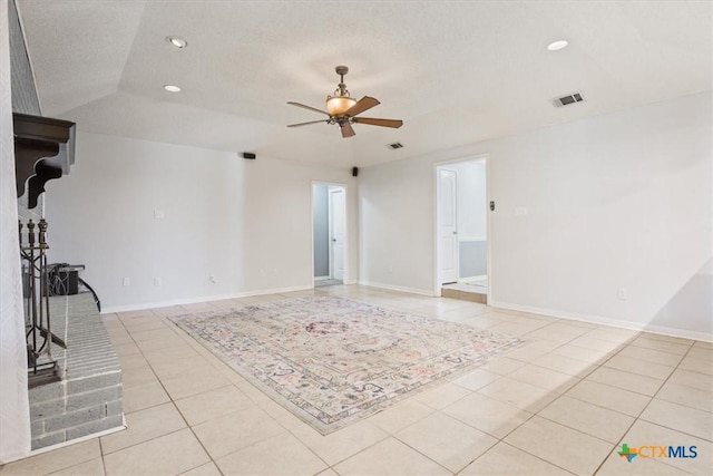 unfurnished living room with ceiling fan, light tile patterned flooring, a textured ceiling, and vaulted ceiling