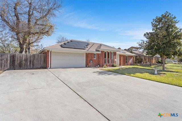 ranch-style home with solar panels, a garage, and a front lawn