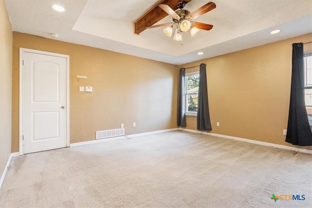 unfurnished room featuring ceiling fan, beam ceiling, light colored carpet, and a textured ceiling