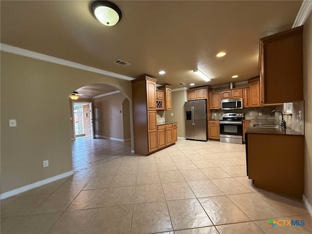 kitchen featuring sink, crown molding, light tile patterned floors, backsplash, and stainless steel appliances