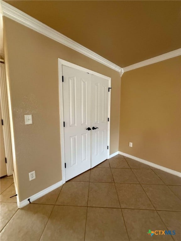 unfurnished bedroom featuring ornamental molding, tile patterned floors, and a closet